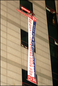 열린우리당 부산시당을 점거하고 있는 덤프연대와 화물연대노동자들이 행진대열을 반기며 펼침막을 내리고 있다. 